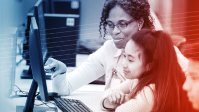 Photo of a teacher helping a young student use elearning software.