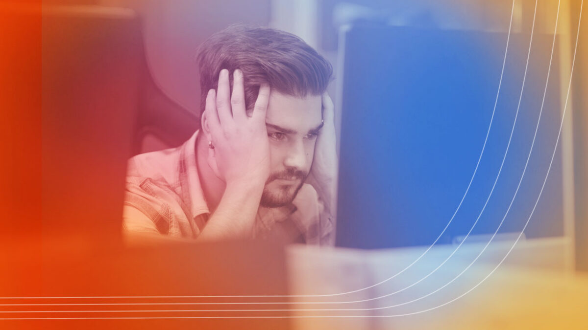 photo of a frustrated software user looking at a monitor and holding the sides of his face